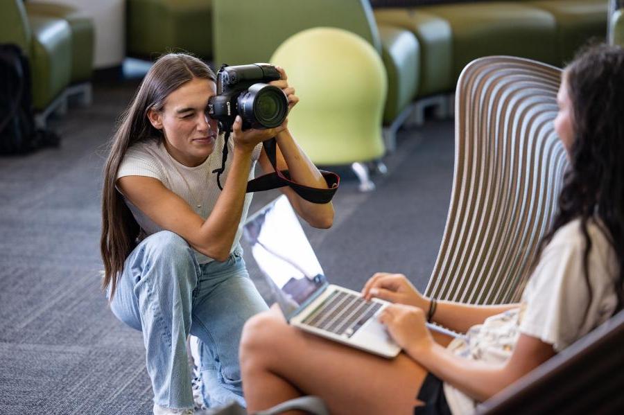 A student taking pictures with a camera for multiplatform journalism.